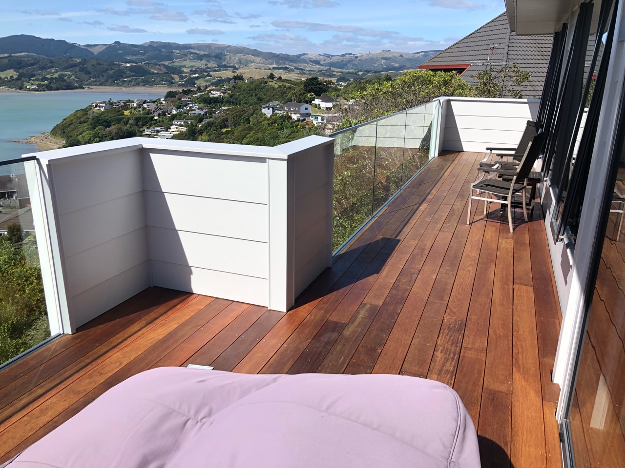 Wellington deck renovation by Smartway Builders. Modern deck with glass safety barrier overlooking Pāuatahanui Inlet, showcasing expert craftsmanship.
